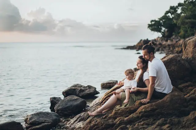 A family travelling Man a Woman and a children Sitting on Rock Near Seashore